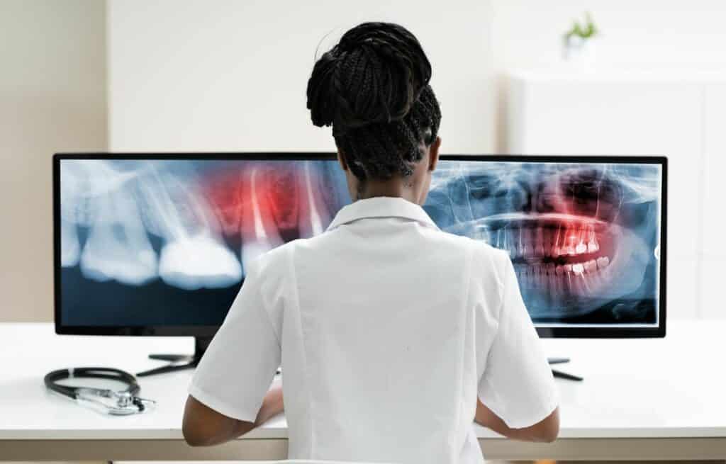 A woman looks at teeth x-rays on a computer screen